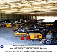 Dans le hangar de la NASA, plein comme la caverne d’Ali Baba, en 1966, on trouve de tout : trois X-15 (&agrave; droite), et trois sortes de lifting bodies: &agrave; gauche, de bas en haut, le HL10, en cours de finition, le M2F3 et le M2F1. Devant la porte se tient le bon vieux C-47, charg&eacute; du  largage du M2F1, juste avant lui un F5D-1 Skylancer et un F4F Phantom !